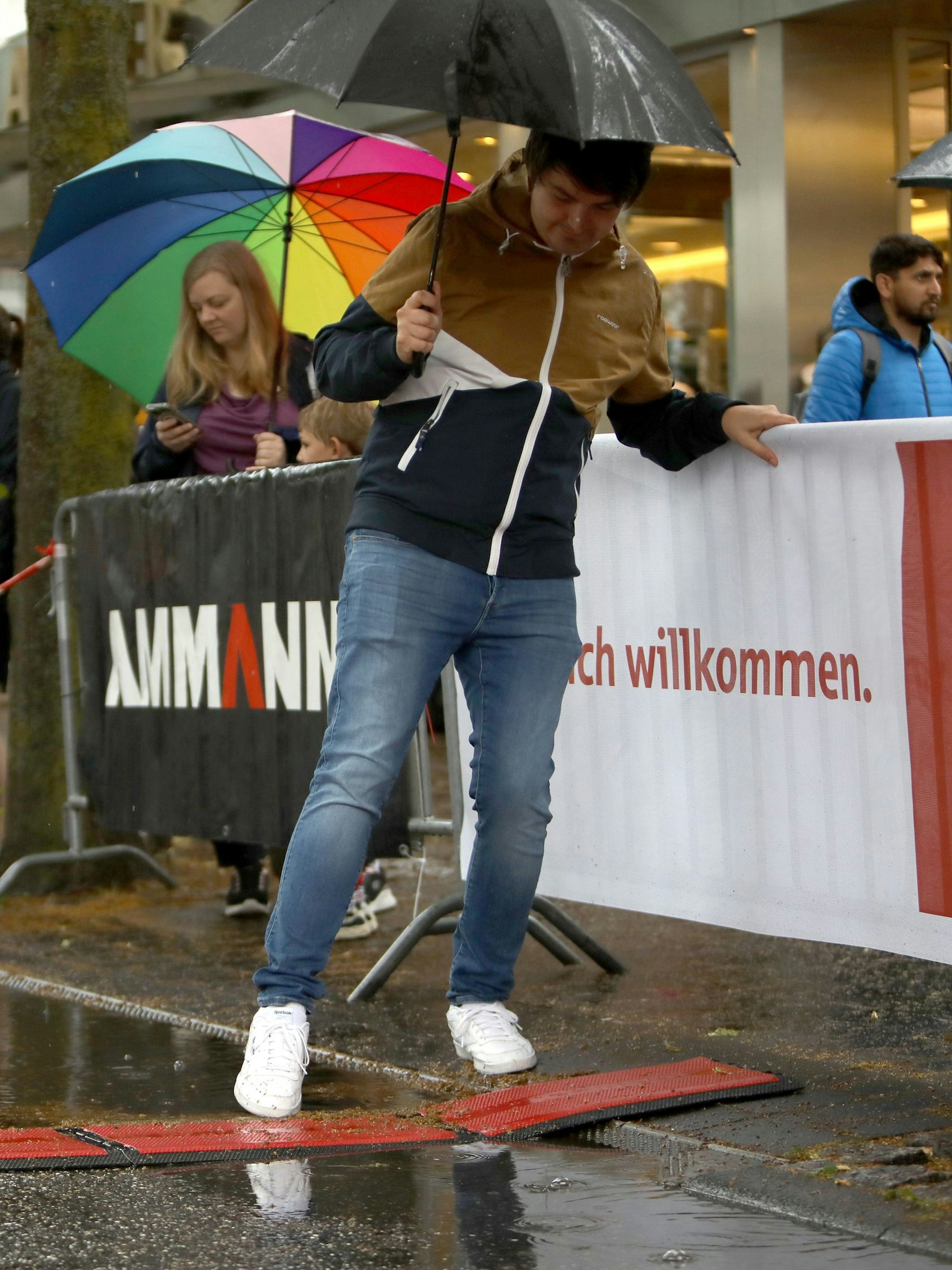 Ein Mann balanciert steht an einem vollgelaufenen Straßenrand.