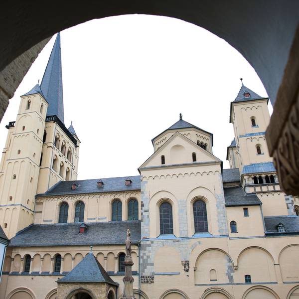 Blick auf die Abteikirche St. Nikolaus in Brauweiler durch einen Torbogen.