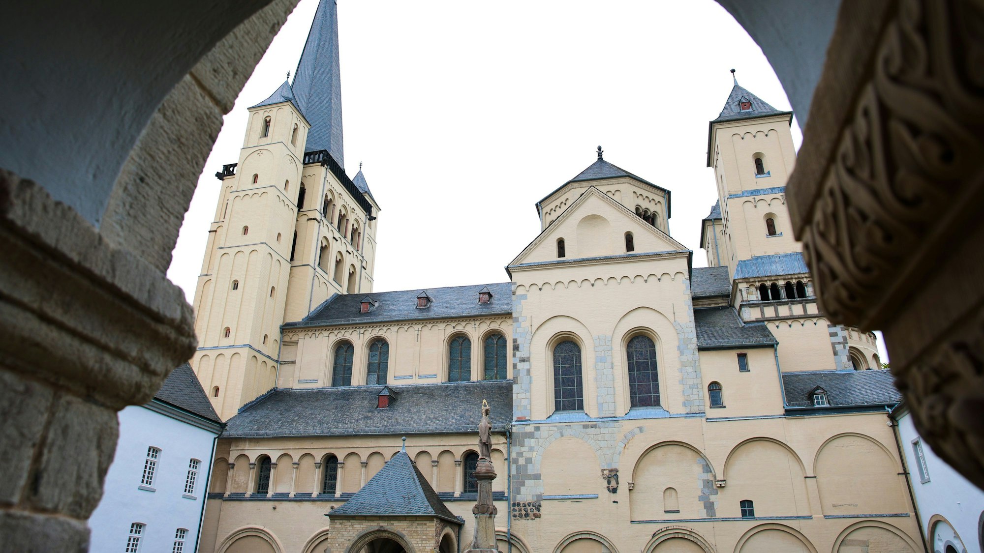 Blick auf die Abteikirche St. Nikolaus in Brauweiler durch einen Torbogen.