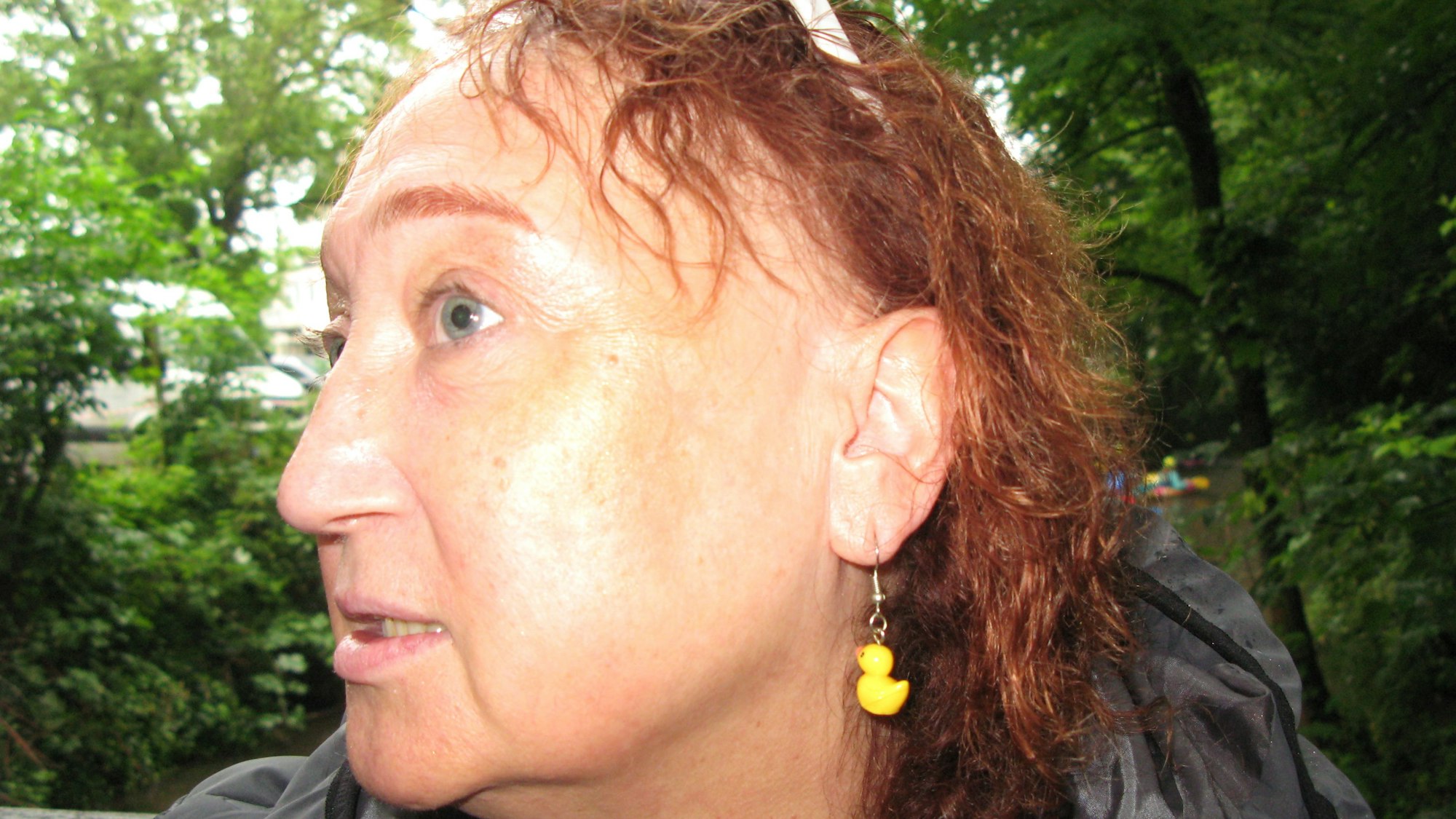 Eine Frau im Profil mit einer gelben Mini-Ente als Ohrhänger.