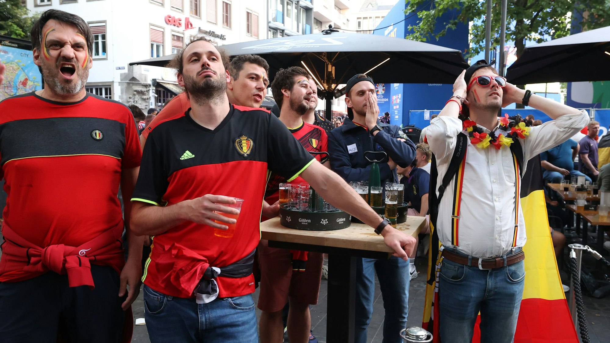 Belgische Fans stehen an einem Stehtisch und schauen das EM-Spiel.