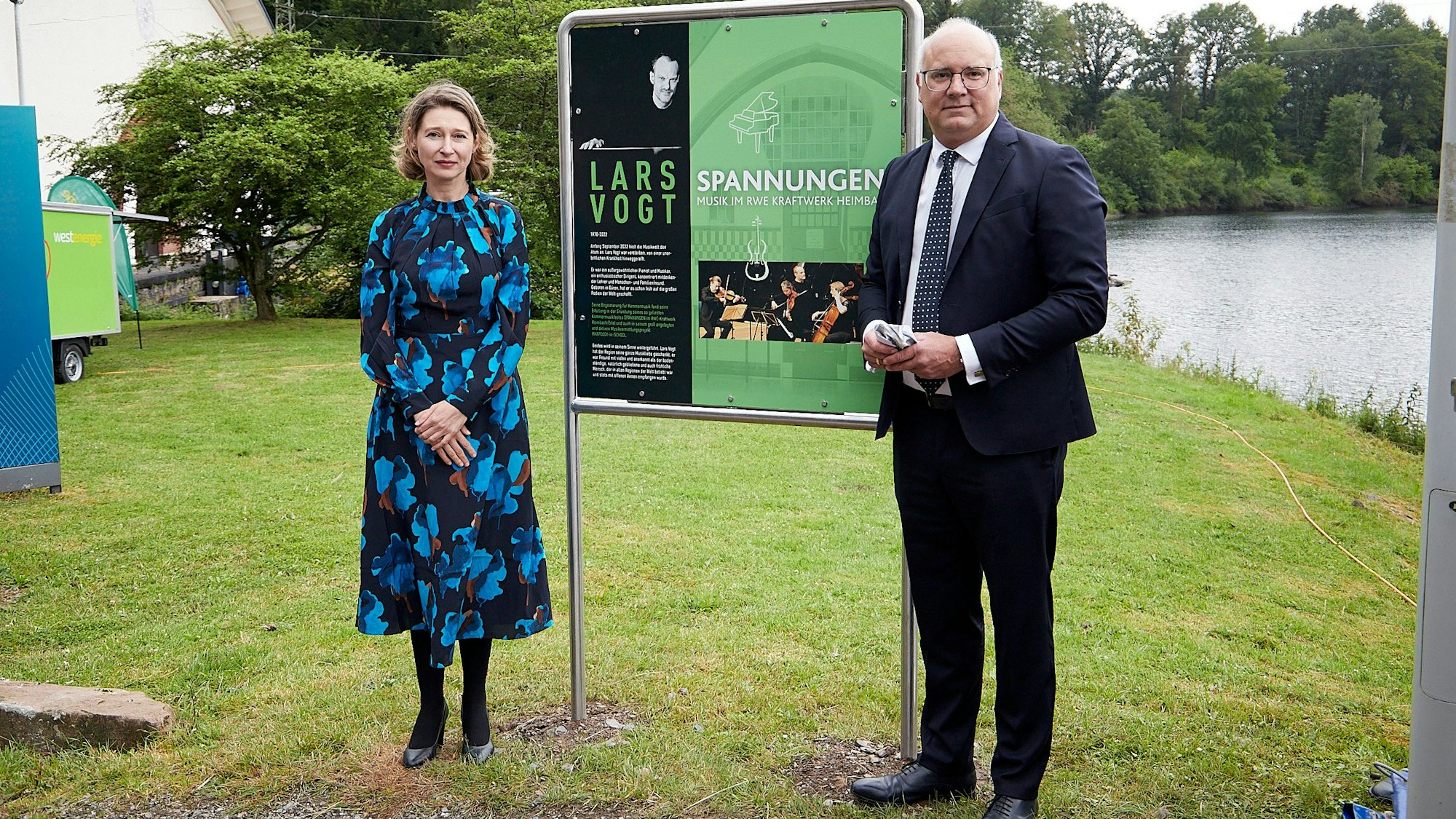 Anna Reszniak-Vogt und Jochen Weiler stehen neben einer Gedenktafel, im Hintergrund ist Wasser zu erkennen.