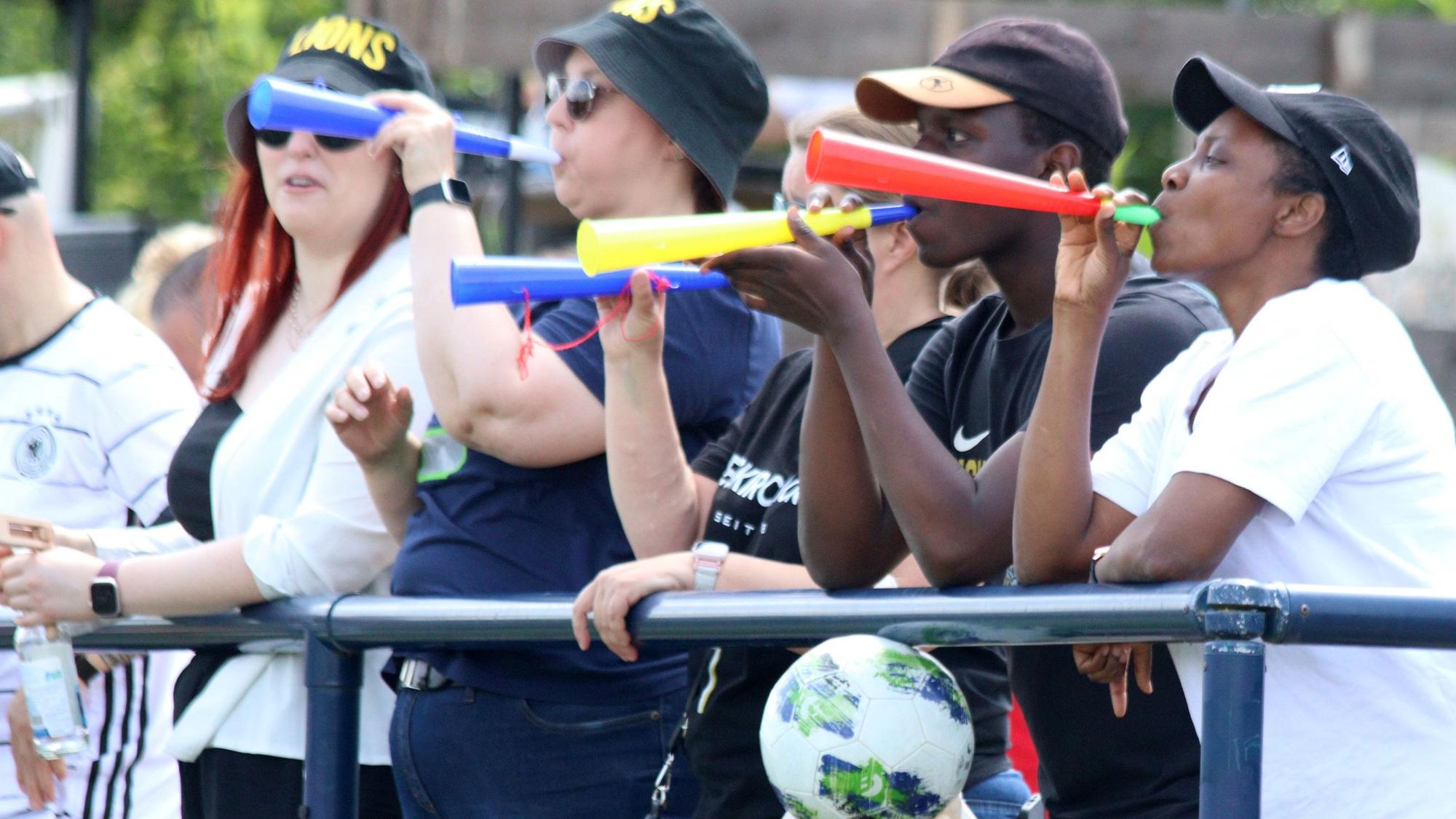 Fans der Euskirchen Lions stehen am Spielfeldrand und blasen in eine Vuvuzela.