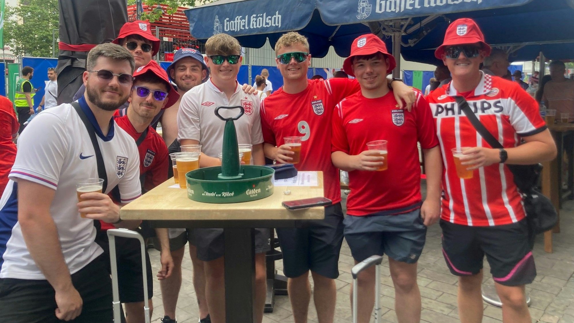 Eine Gruppe junger Männer steht um einen Kranz Bier herum.