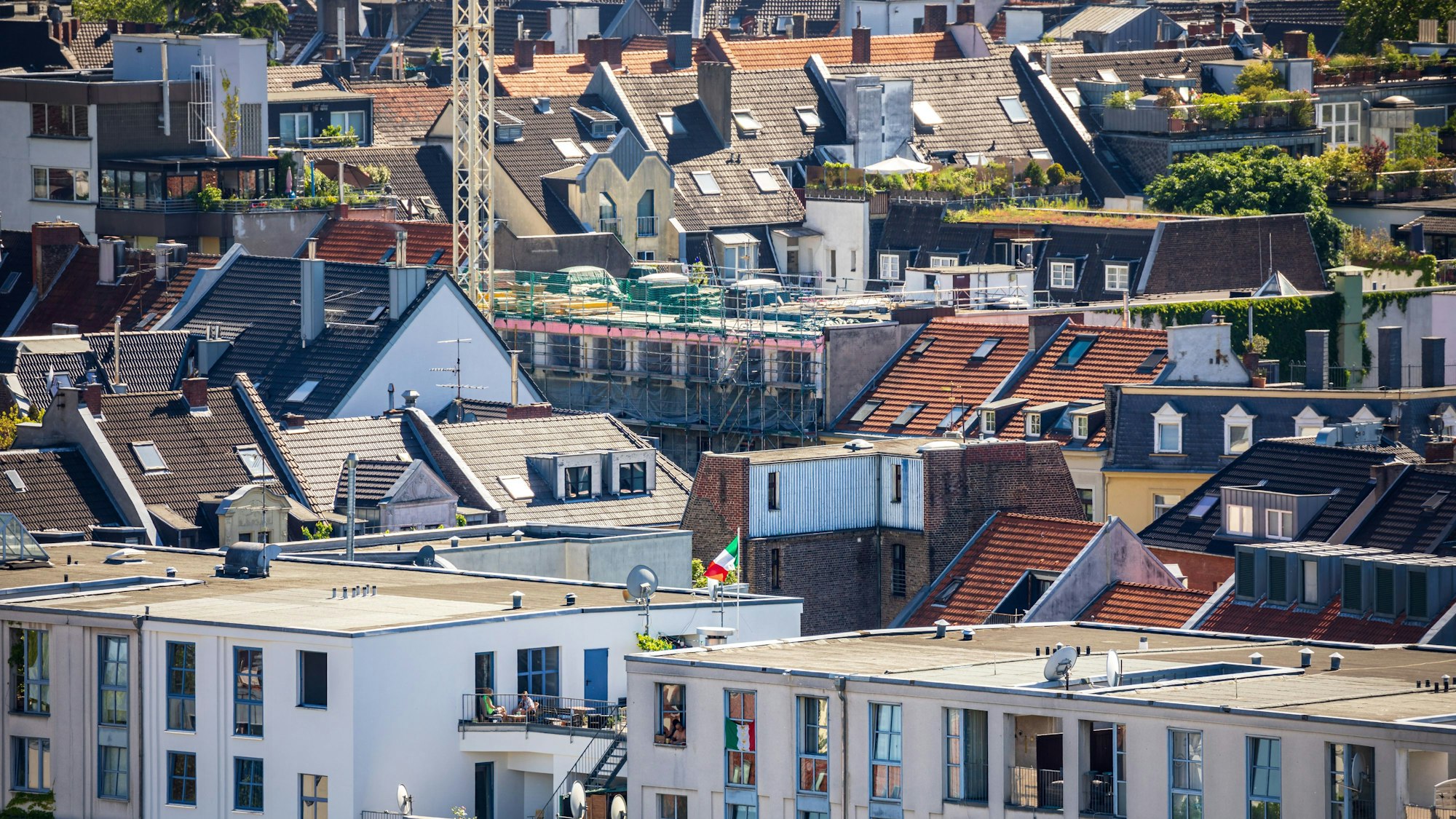 Dächer von Gebäuden von modern bis historisch sind im Severinsviertel in der Kölner Südstadt zu sehen. In der Mitte ist eine Baustelle sichtbar.