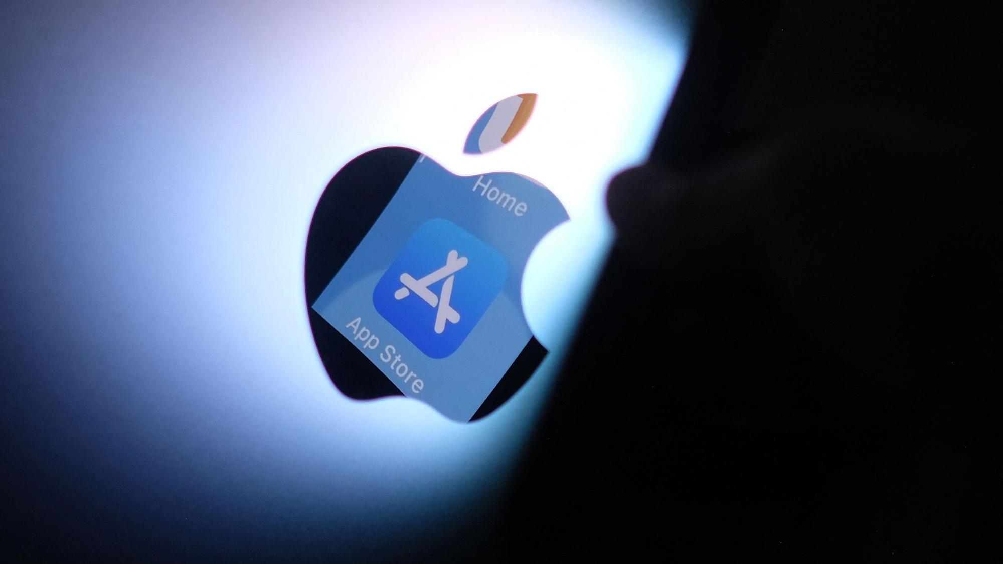 Das Apple App Store Logo wird von einem iPhone auf der Rückseite eines iMacs reflektiert. (Symbolbild)