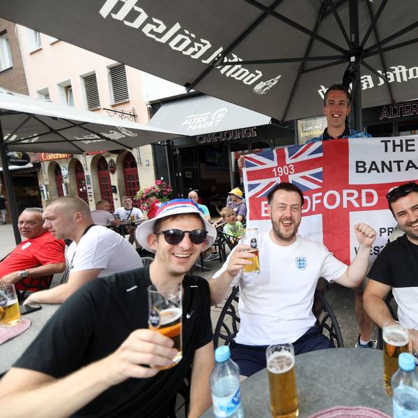 Englandfans sitzen am Alter Markt in einem Restaurant und prosten mit einem Glas Bier in die Kamera.