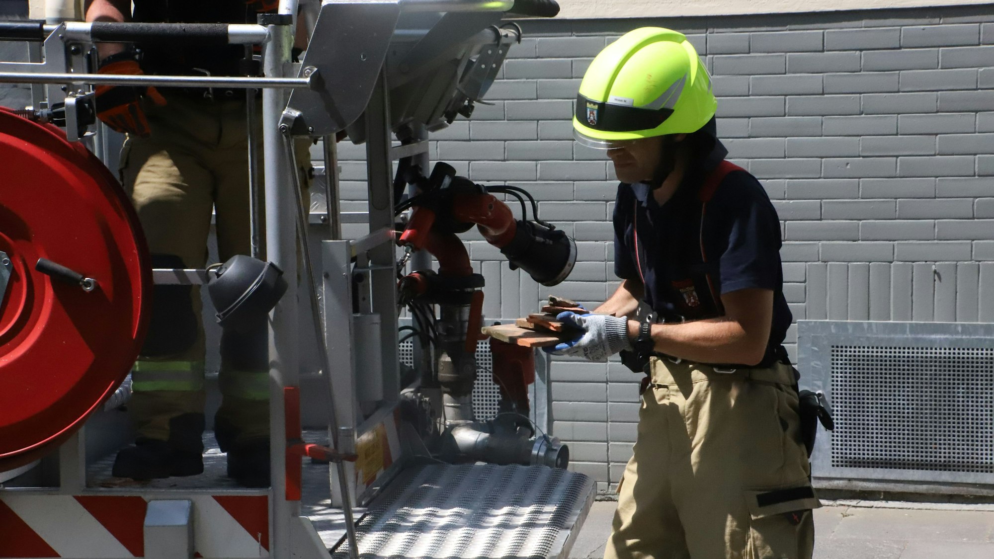Ein Feuerwehrmann hat kaputte Dachziegel und Mörtel in den Händen.