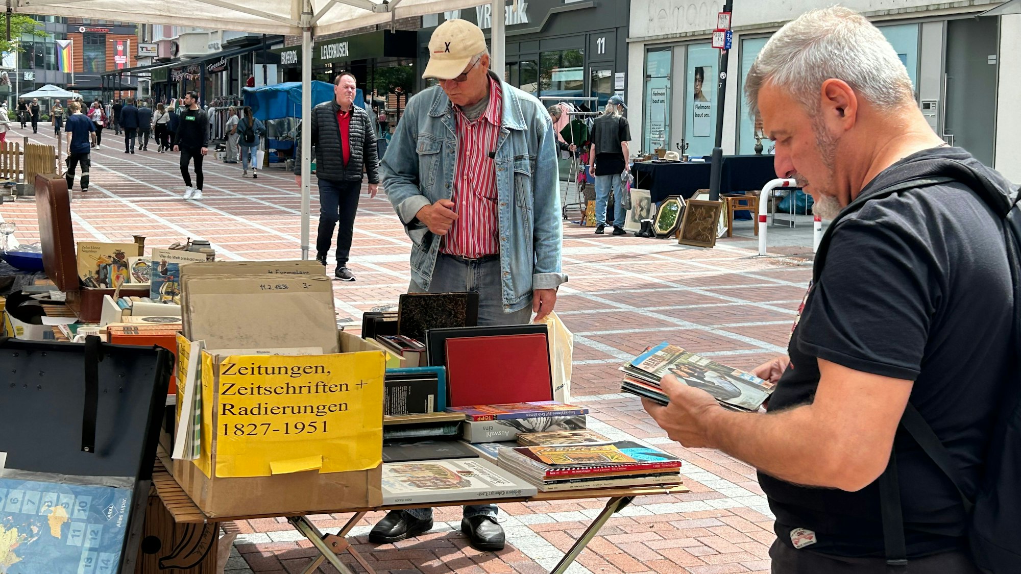 Mit „Papier & Schätze“ soll sich ein Trödelmarkt in Wiesdorf etablieren. Zu sehen: stöbernde Besucher in der Fußgängerzone.