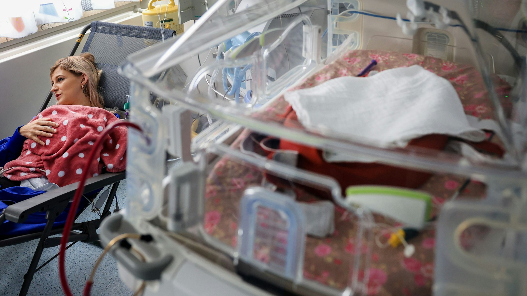 Ein Frühchen, geboren mit 22 Wochen, liegt auf der neonatologischen Intensivstation der Frauenklinik Köln. Vanessa Janssen kuschelt mit ihrer Tochter neben dem Inkubator.