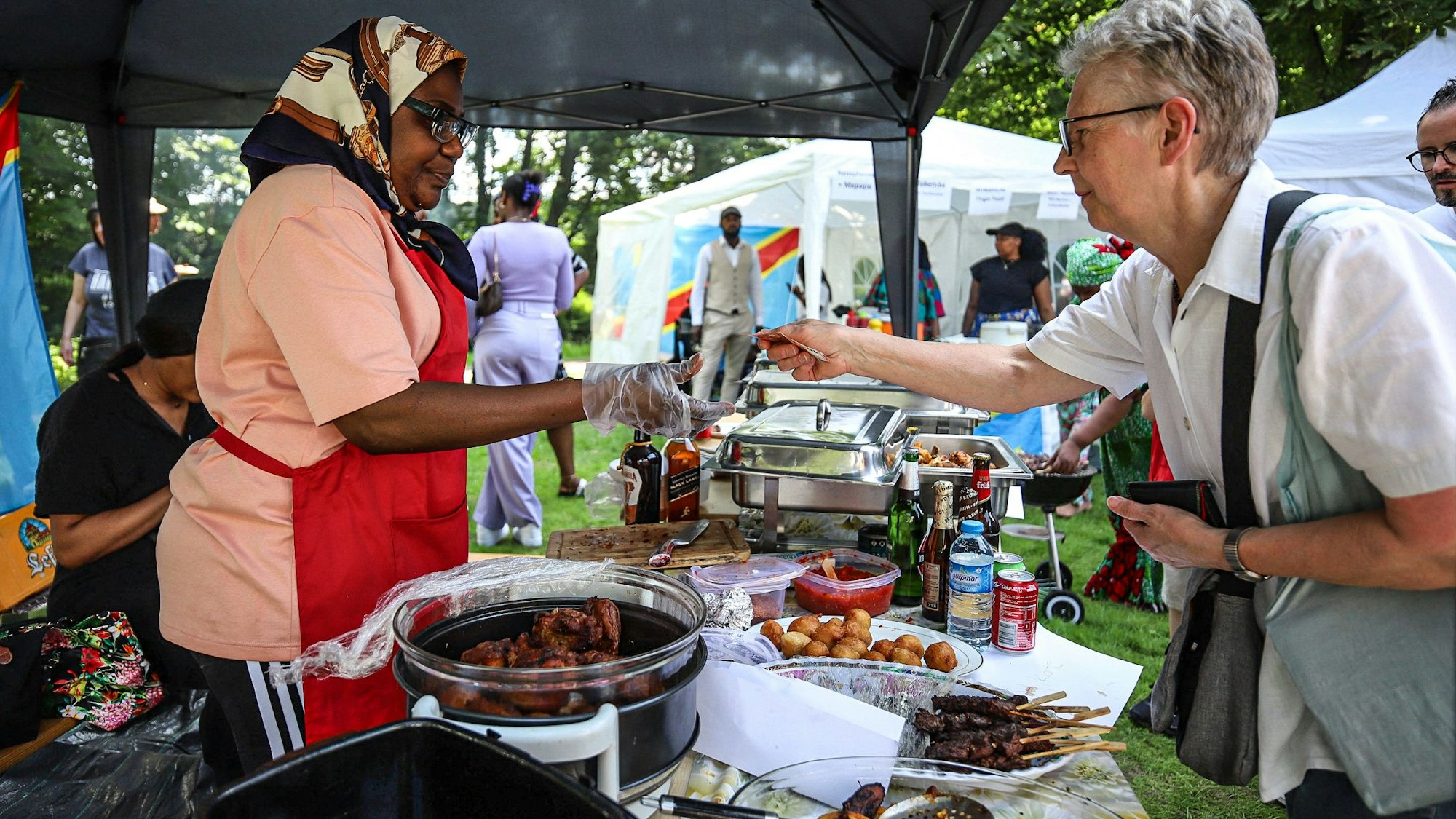 Eine Frau bedient eine Kundin an einem Essensstand.