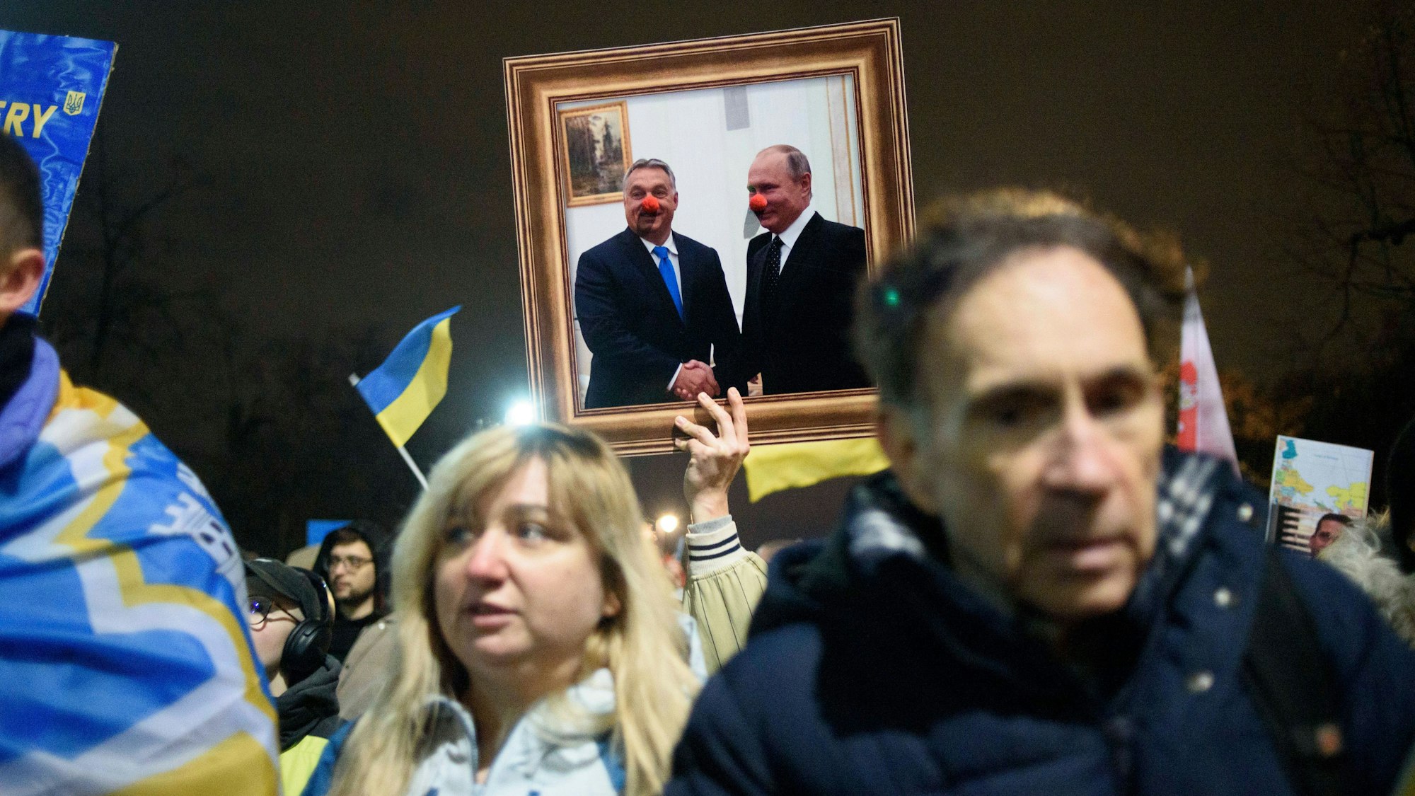 Ein Demonstrant hält in Warschau ein Bild von Kremlchef Wladimir Putin und dem ungarischen Ministerpräsidenten Viktor Orbán in die Luft, beide Staatschef tragen darauf Clownsnasen. (Archivbild)