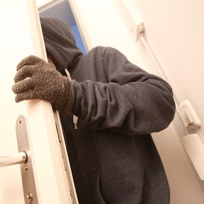 Das Bild ist ein Symbolfoto und zeigt, wie eine maskierte Person in eine Wohnung eindringt.
