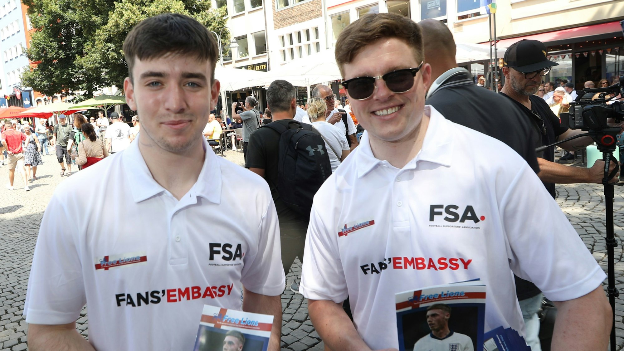 Zwei junge Männer zeigen die Flyer, die sie für die Englandfans verteilen.