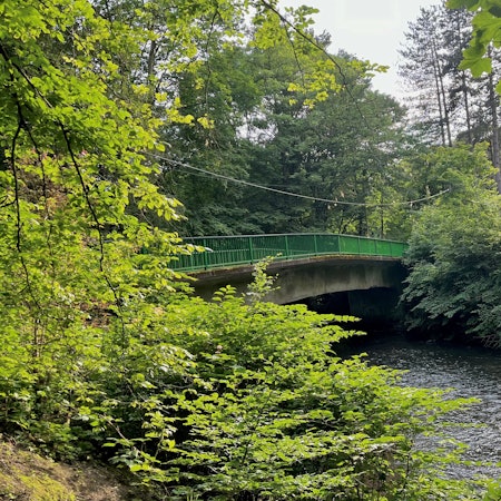 Eine baufällige Brücke überspannt einen Fluss.
