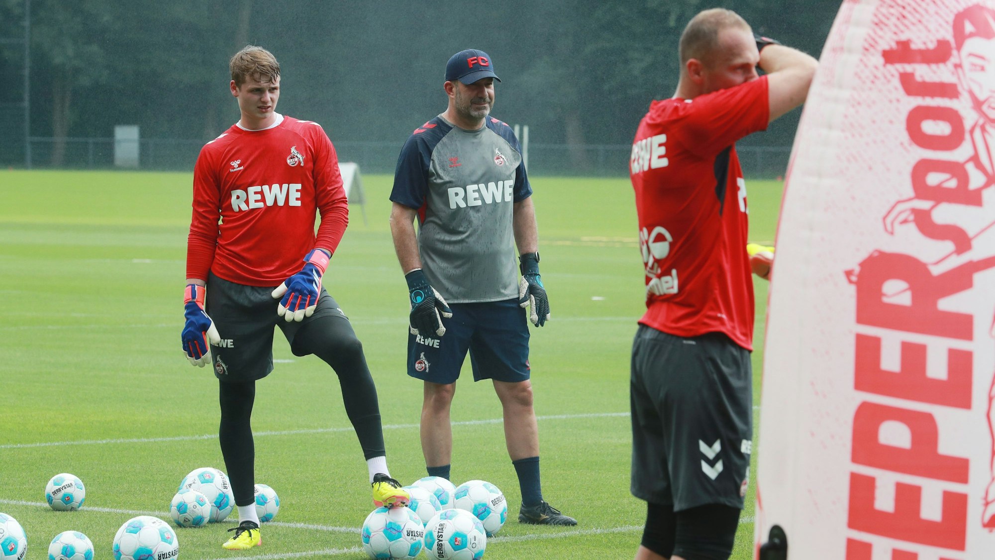 Kölns Torwarttrainer Peter Greiber (M.) leitet die FC-Keeper Jonas Urbig (l.) und Marvin Schwäbe an.
