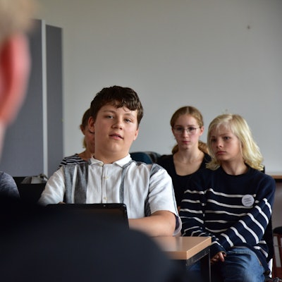 Mehrere Schüler sitzen in einer Klasse.