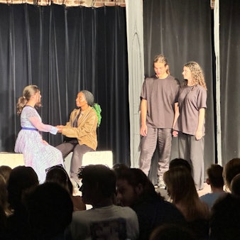Junge Leute spielen Theater auf einer Bühne.