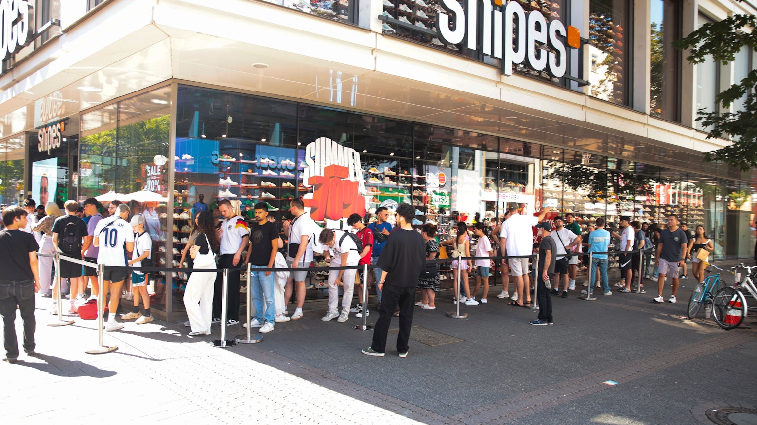 Vor dem Snipes Store auf der Schildergasse steht eine lange Schlange mit jungen Leuten.