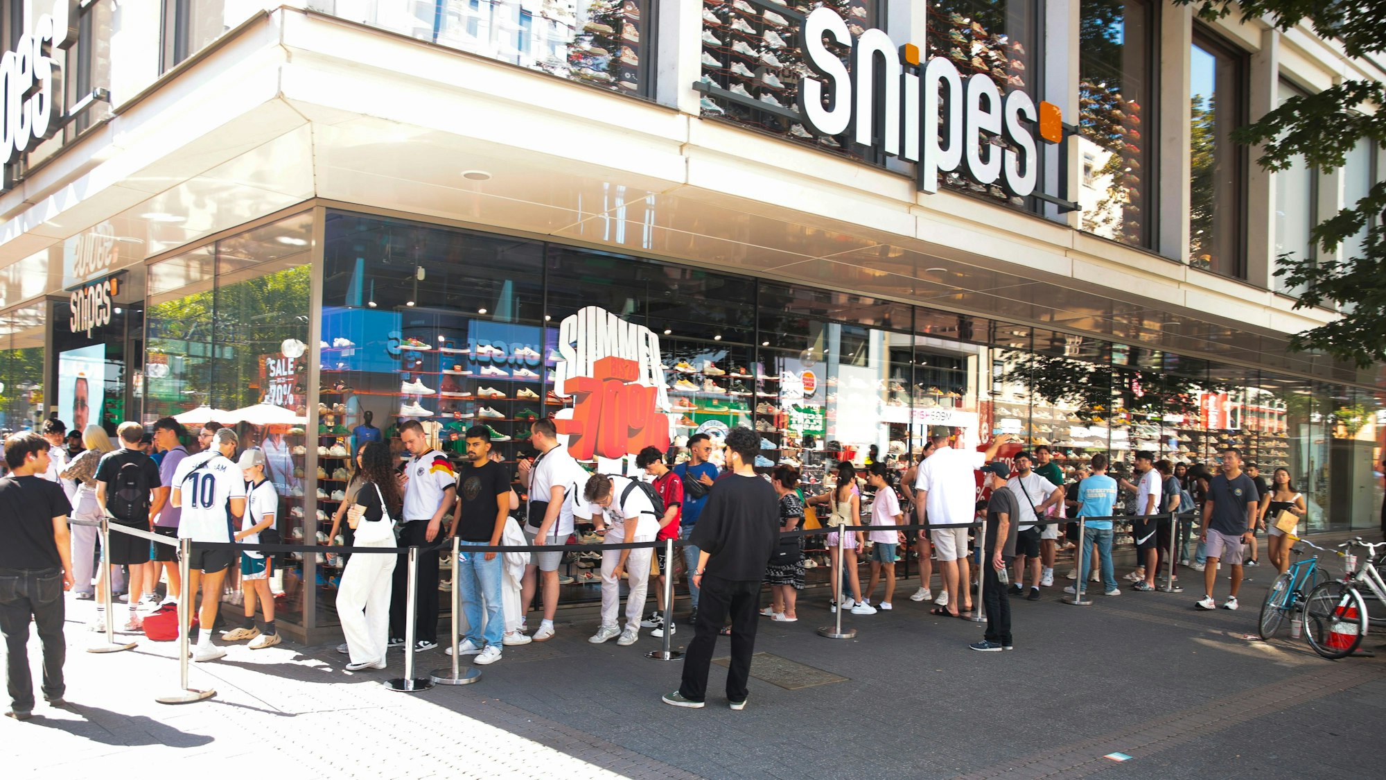 Vor dem Snipes Store auf der Schildergasse steht eine lange Schlange mit jungen Leuten.