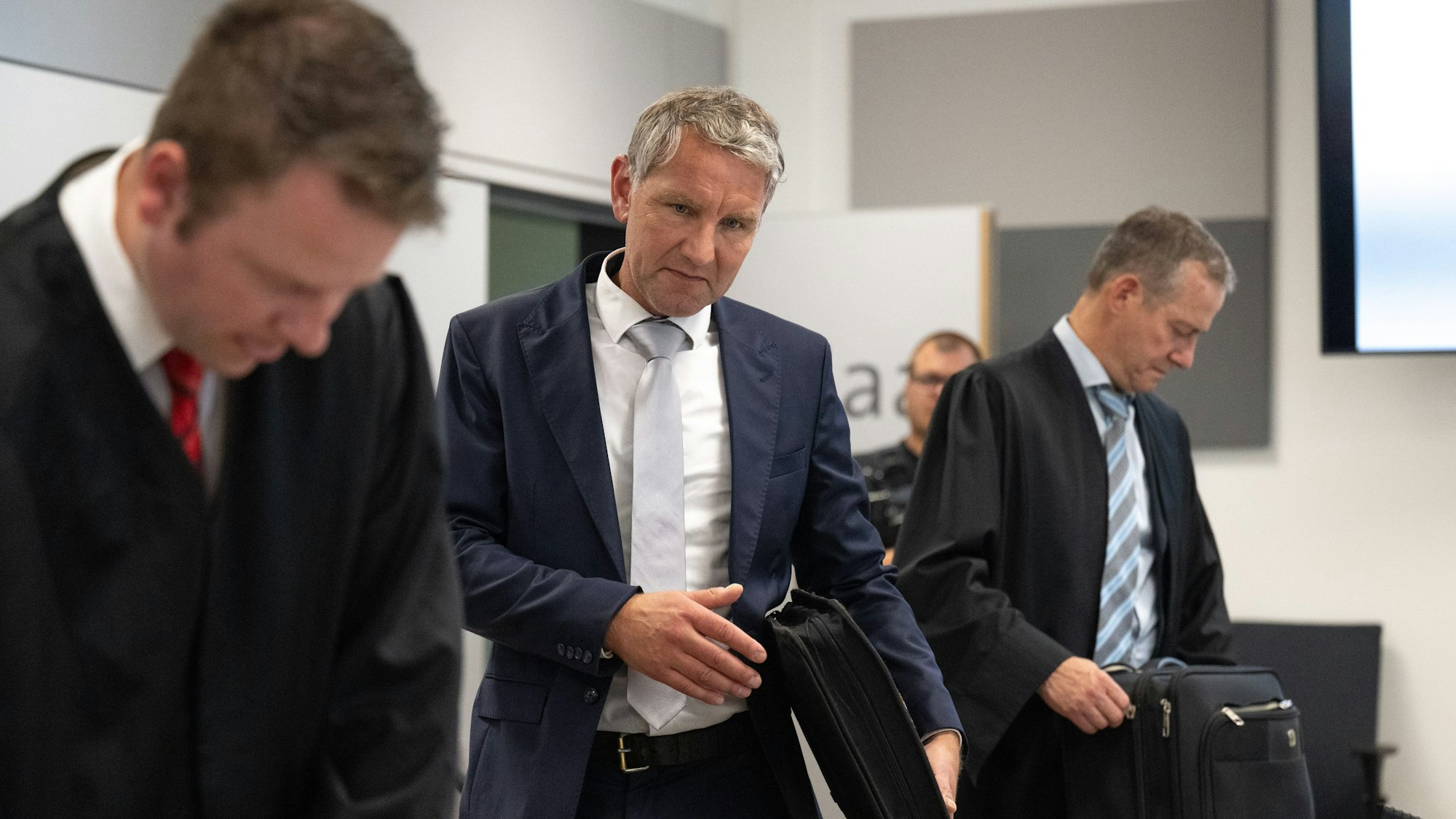 Björn Höcke (M), Vorsitzender der Thüringer AfD, kommt nach seinen Anwälten Florian Gempe (l) und Ralf Hornemann in den Saal des Landgerichts Halle/Saale.