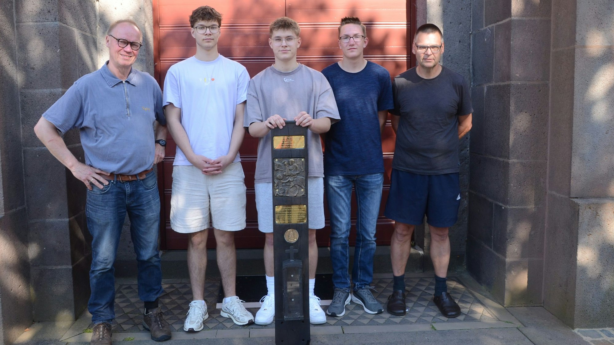 Fünf Männer stehen vor der Eingangstür einer Kirche.