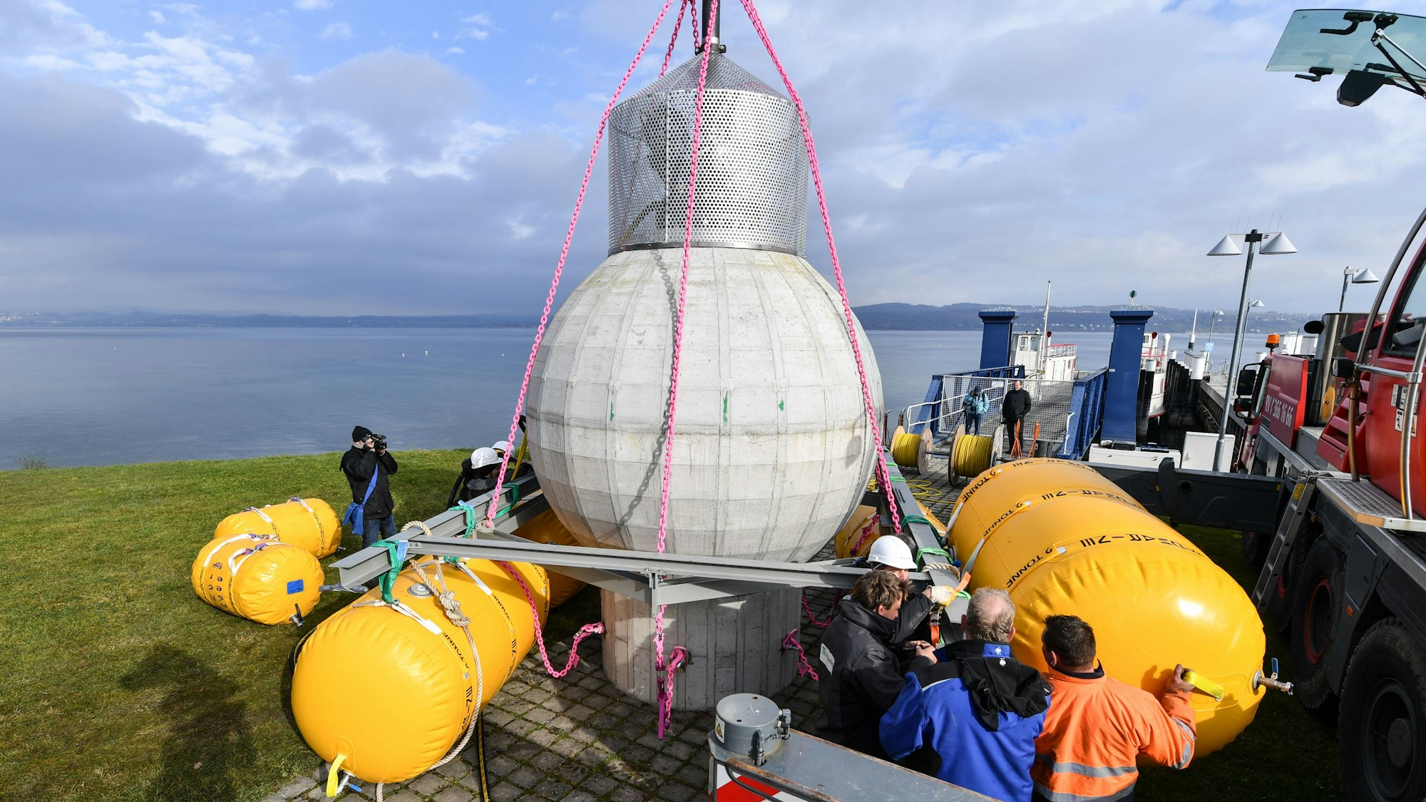 Mitarbeiter des Fraunhofer-Instituts bereiten am 08.11.2016 in Konstanz (Baden-Württemberg) unmittelbar am Ufer des Bodensees einen Kugelspeicher aus Beton vor, um diesen später im Bodensee für wenige Wochen zu Testzwecken zu versenken. Mit der Kugel, die einen Durchmesser von drei Metern hat, soll nach Institutsangaben getestet werden, ob sie unter Wasser als Energiespeicher dienen kann. Foto: Felix Kästle/dpa ++ +++ dpa-Bildfunk +++