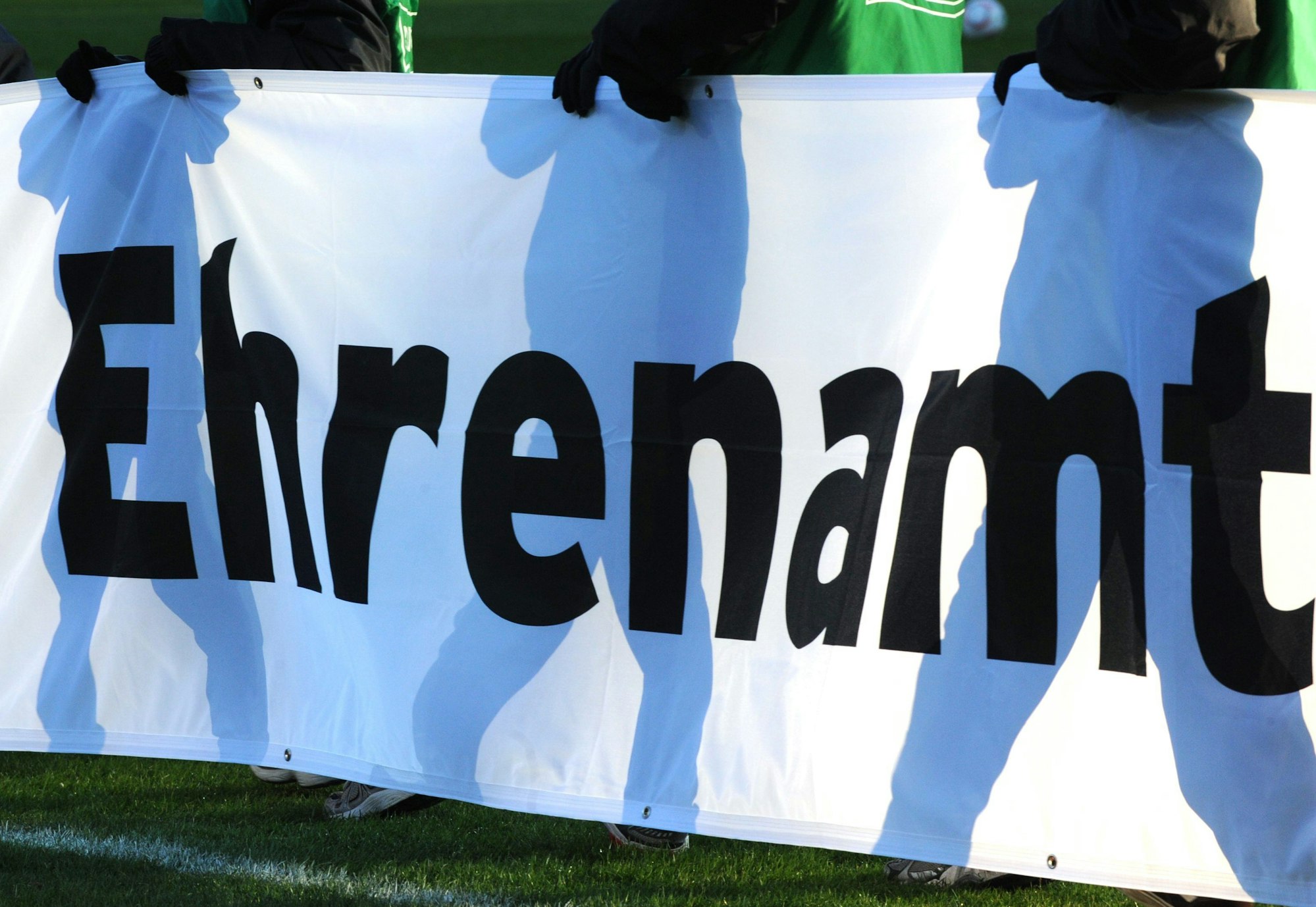 Jugendliche halten ein Banner mit der Aufschrift „Ehrenamt“ in den Händen.