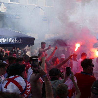 Zu sehen sind Fußballfans mit Rauchbomben und Bengalos.