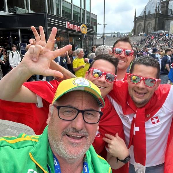 EM-Volunteer Mike Pütz in Köln mit vier jubelnden Fußballfans aus der Schweiz in rot-weißem Outfit.