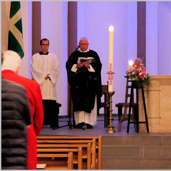 Ein Pfarrer steht am Altar von St. Nikolaus Bensberg, rechts ist neben Kerzen ein Bild des verstorbenen Heimatforschers Willi Fritzen zu sehen.