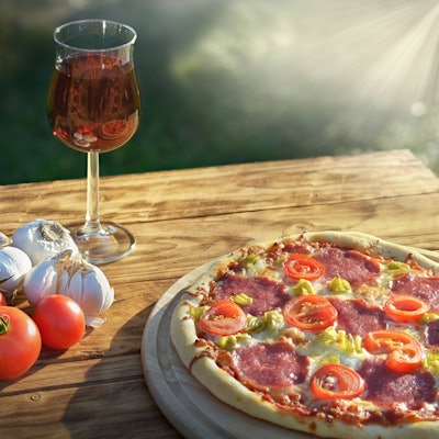 Gemüse, Wein und eine Pizza auf einem Holztisch.
