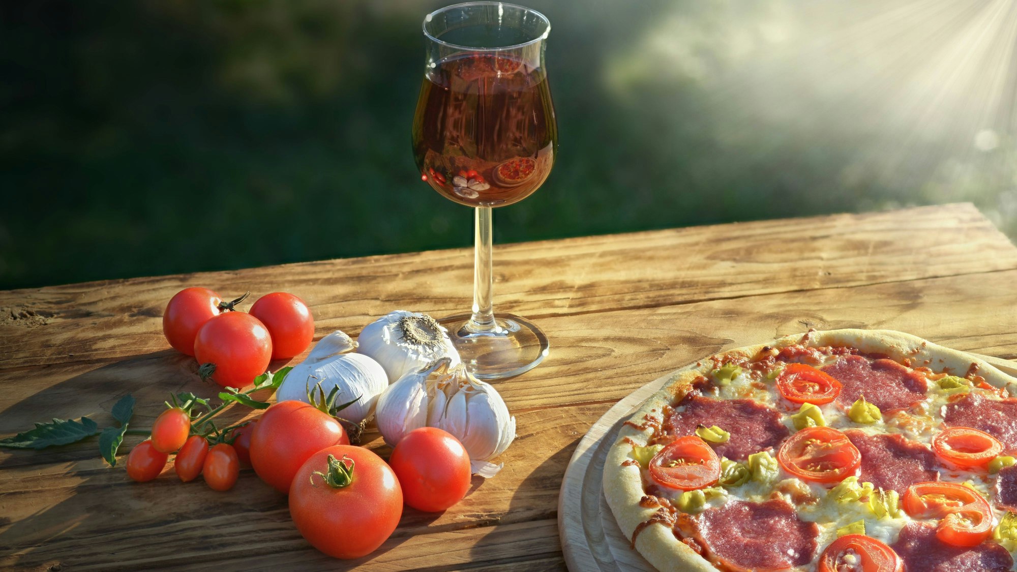 Gemüse, Wein und eine Pizza auf einem Holztisch.