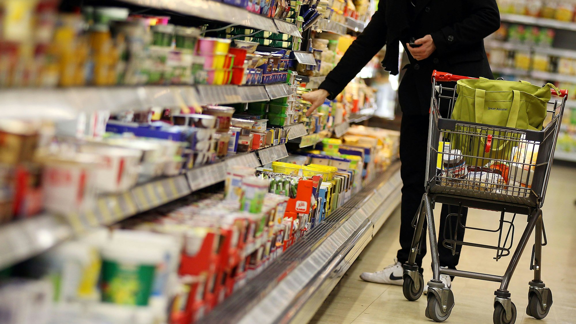 Ein Kunde steht vor einem Supermarktregal.