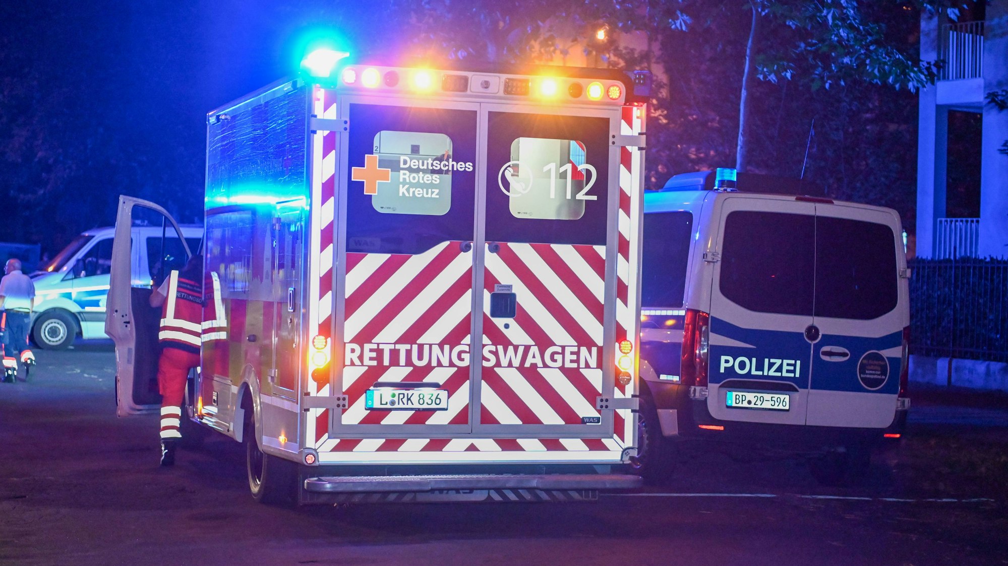 Ein Krankenwagen und ein Einsatzwagen der Polizei stehen mit Blaulicht auf einer Straße während eines Einsatzes. (Symbolbild)