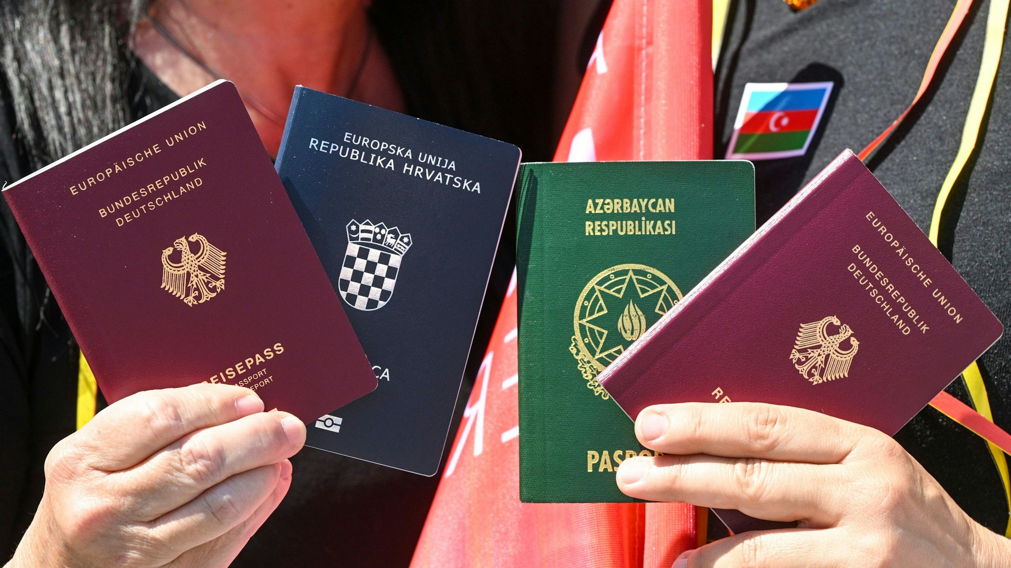 Menschen zeigen bei einem Fototermin zur Unterstützung des neuen Staatsangehörigkeitsrecht die beiden Pässe, den deutschen und den kroatischen und aserbaidschanischen.
