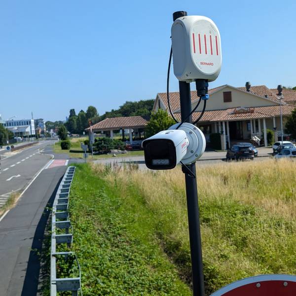 Das Foto zeigt eine Überwachungskamera auf einem Mast am Straßenrand.