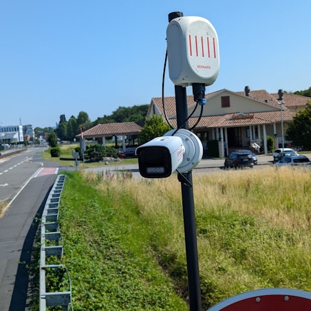Das Foto zeigt eine Überwachungskamera auf einem Mast am Straßenrand.
