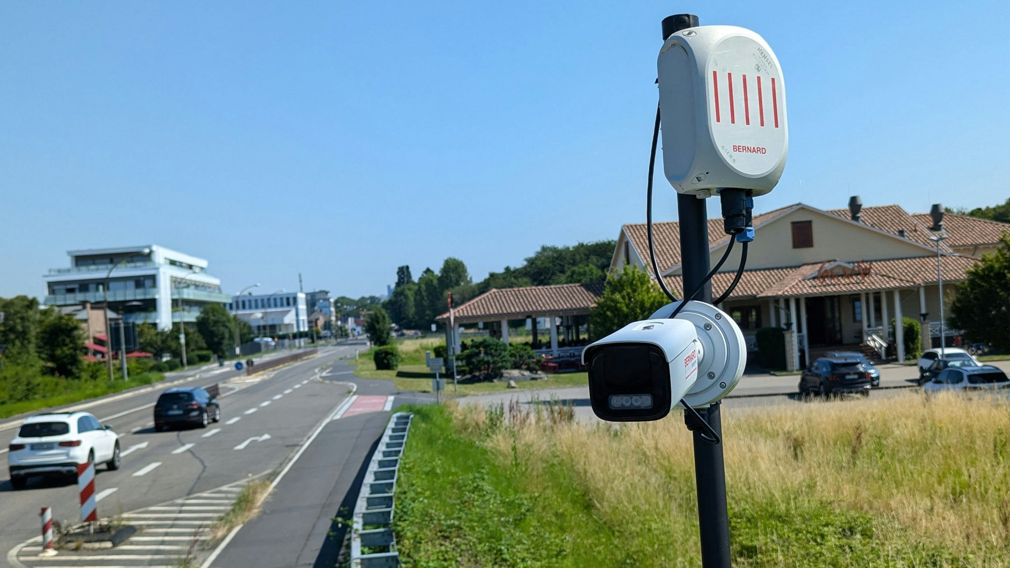 Das Foto zeigt eine Überwachungskamera auf einem Mast am Straßenrand.