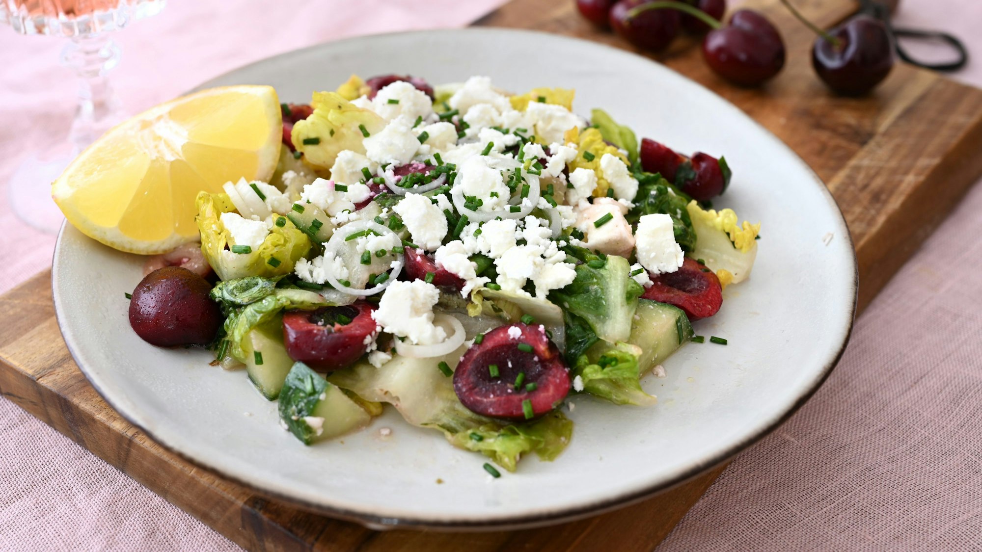 Der Salat mit Feta-Käse und Kirschen ist auf einem Teller angerichtet.