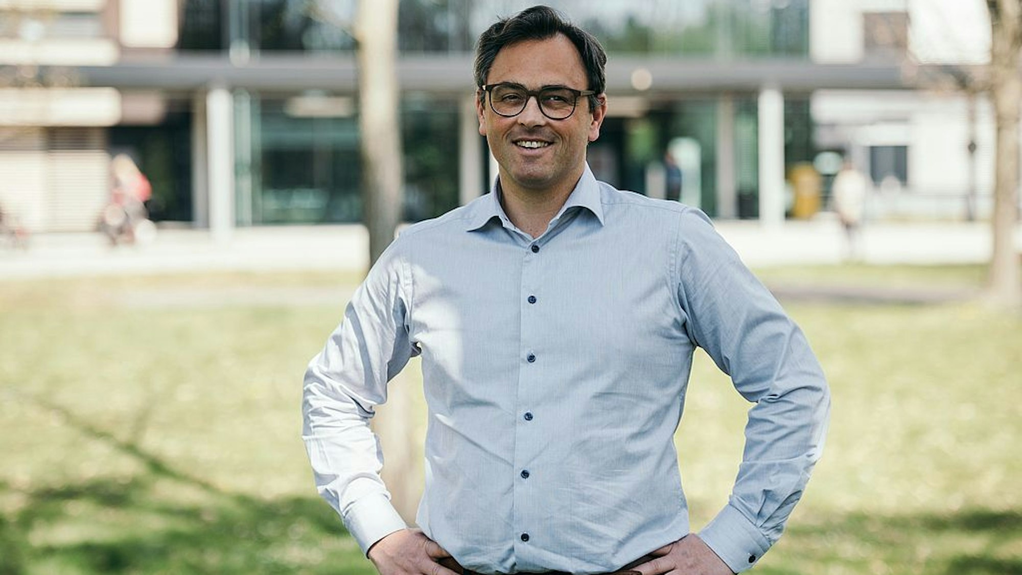Christian Karagiannidis steht vor dem Krankenhaus Merheim. Er trägt ein hellblaues Hemd.