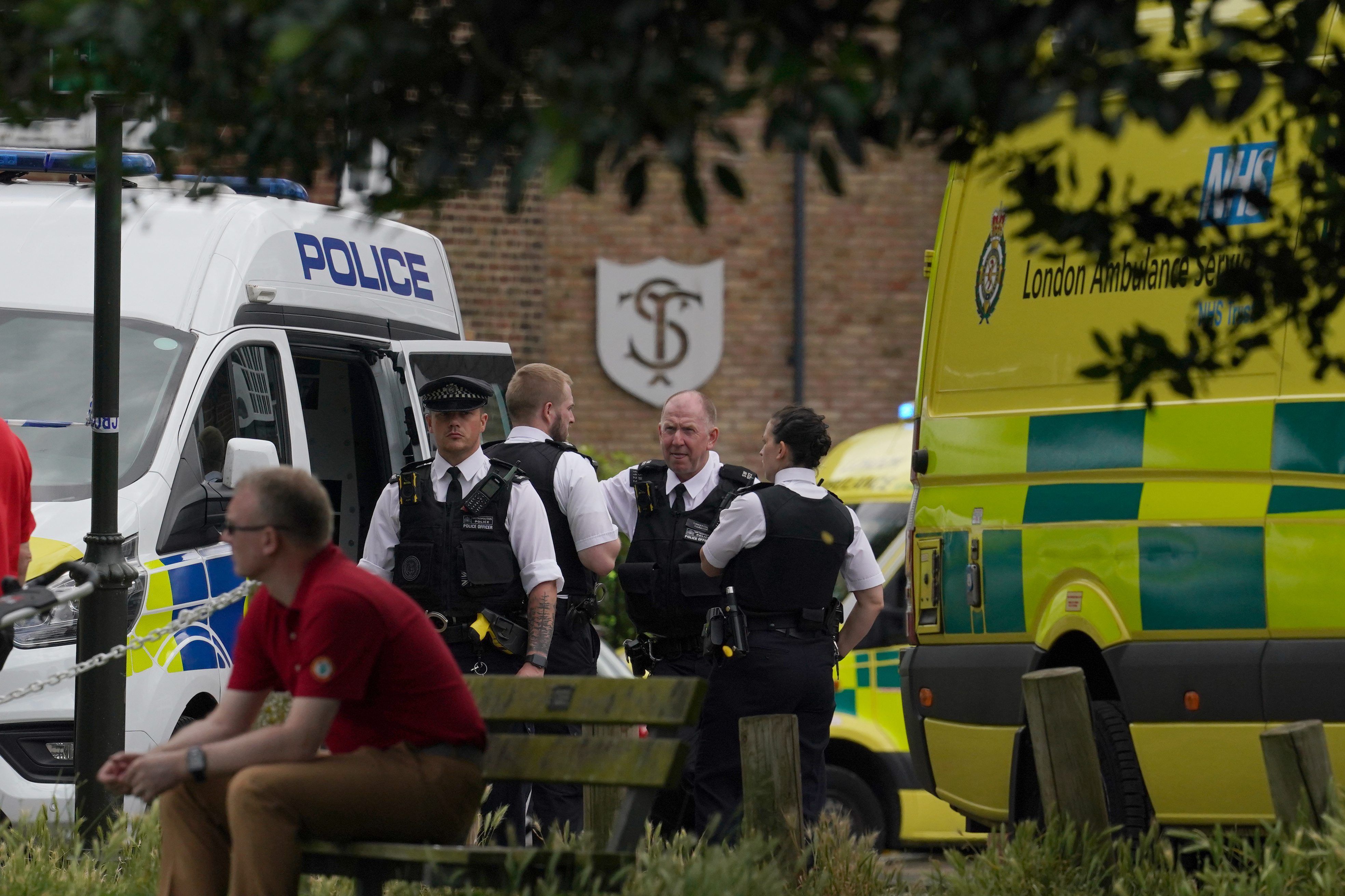 ARCHIV - 06.07.2023, Großbritannien, London: Polizisten treffen am Einsatzort ein. Im Hintergrund sind Polizeiautos und die Schule zu sehen.