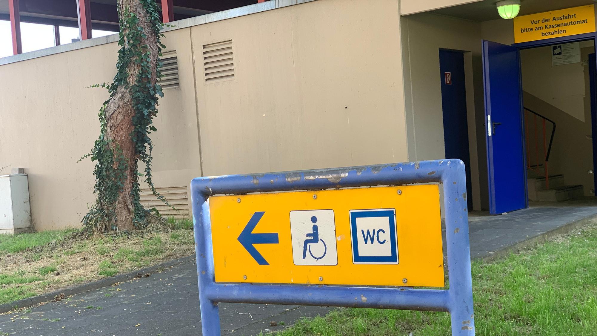 Vor dem Parkhaus Entenpfuhl steht ein Schild, das den Weg zur WC-Anlage weist.