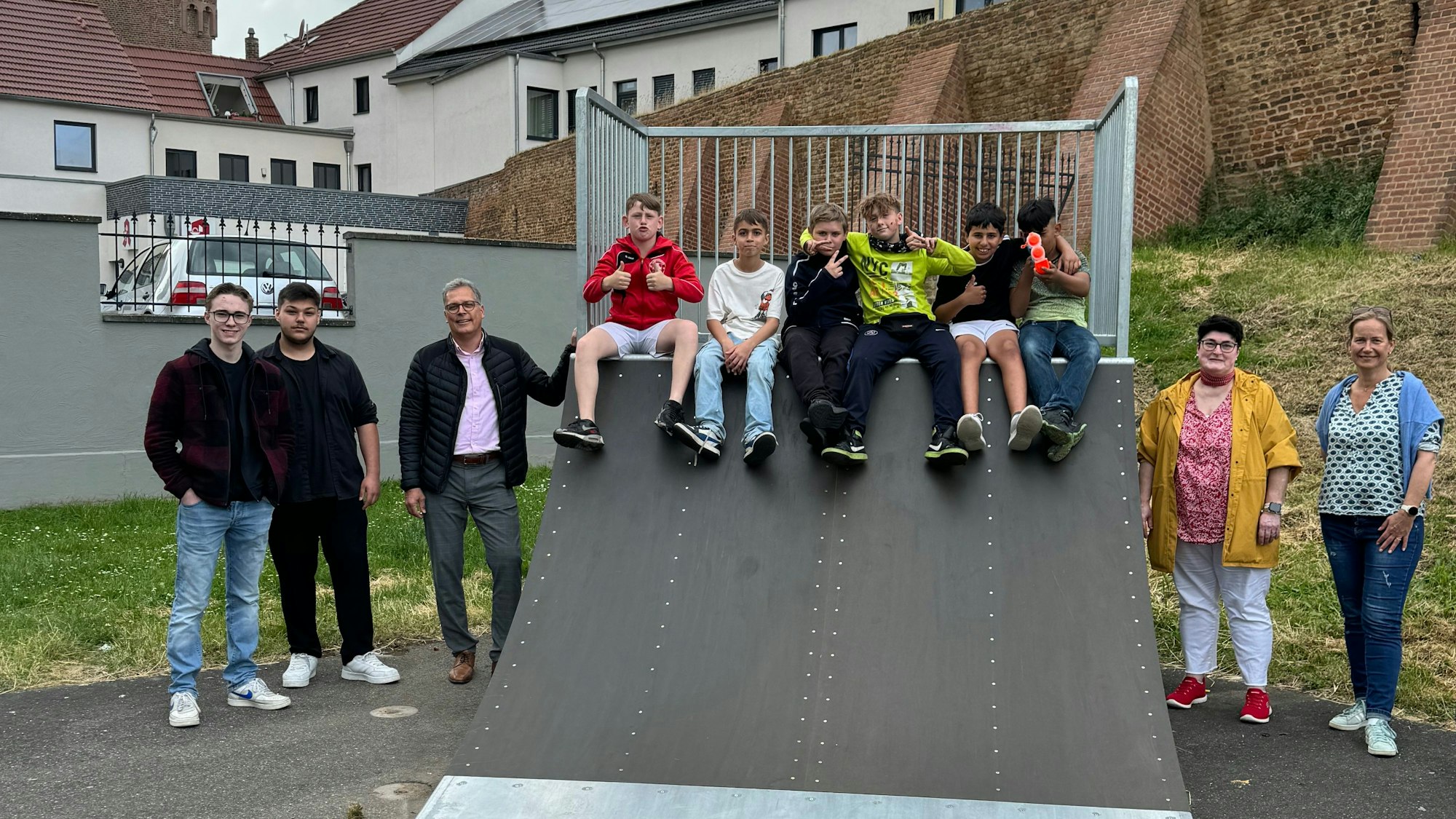 Die Beteiligten stehen neben einer Skaterampe am Frankengraben, auf der sechs Jugendliche sitzen.