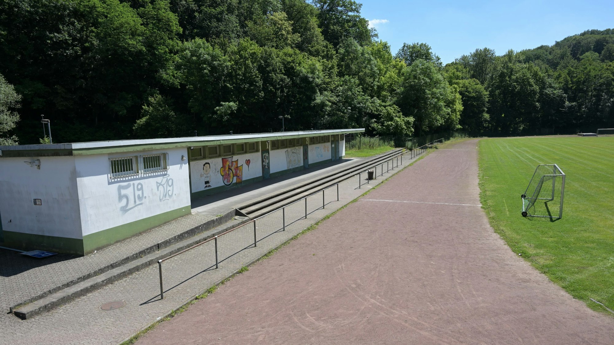 Laufbahn und alte Umkleidekabinen eines Sportplatzes.