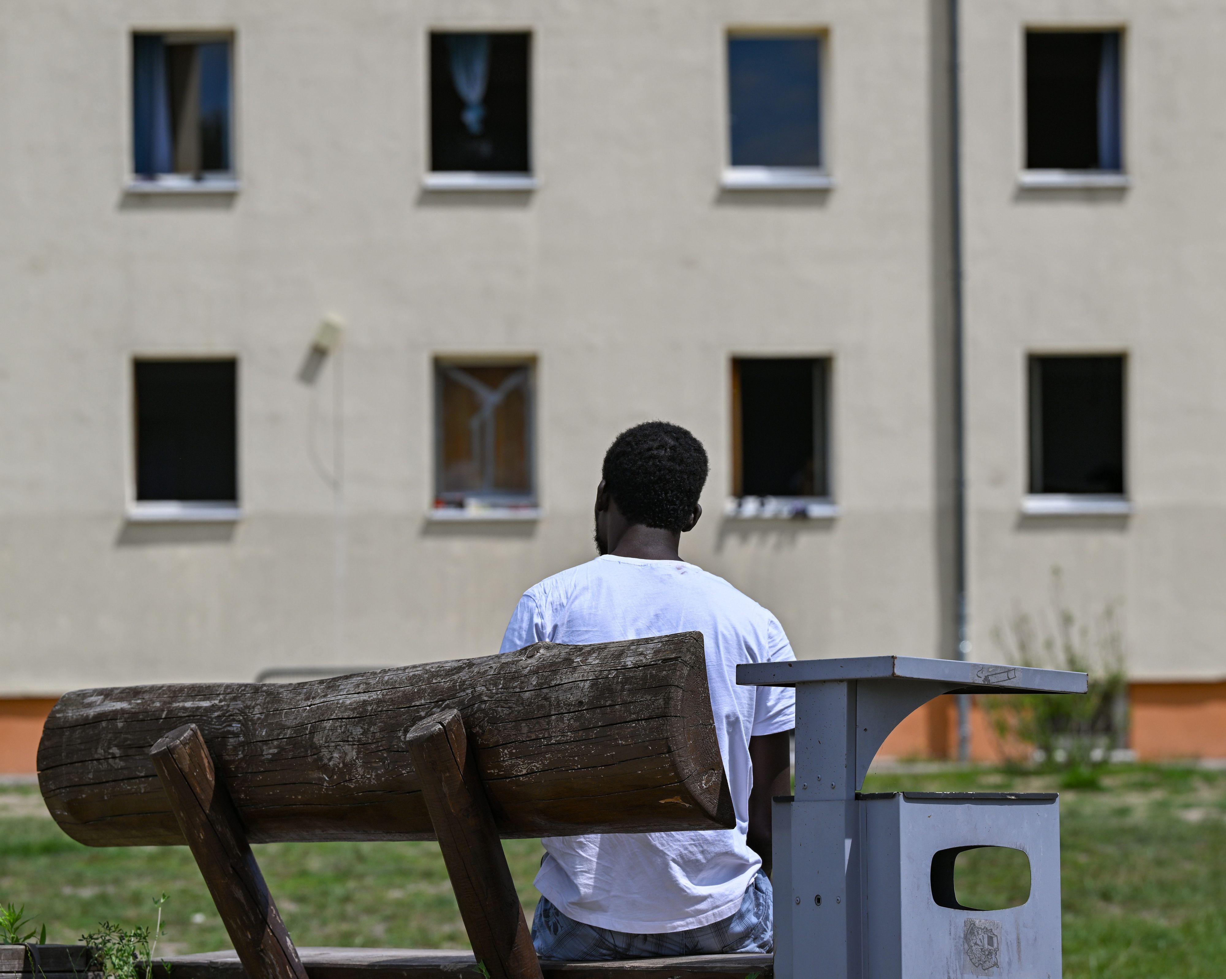 Ein Migrant sitzt auf einer Bank auf dem Gelände der Zentralen Erstaufnahmeeinrichtung für Asylbewerber (ZABH) des Landes Brandenburg.