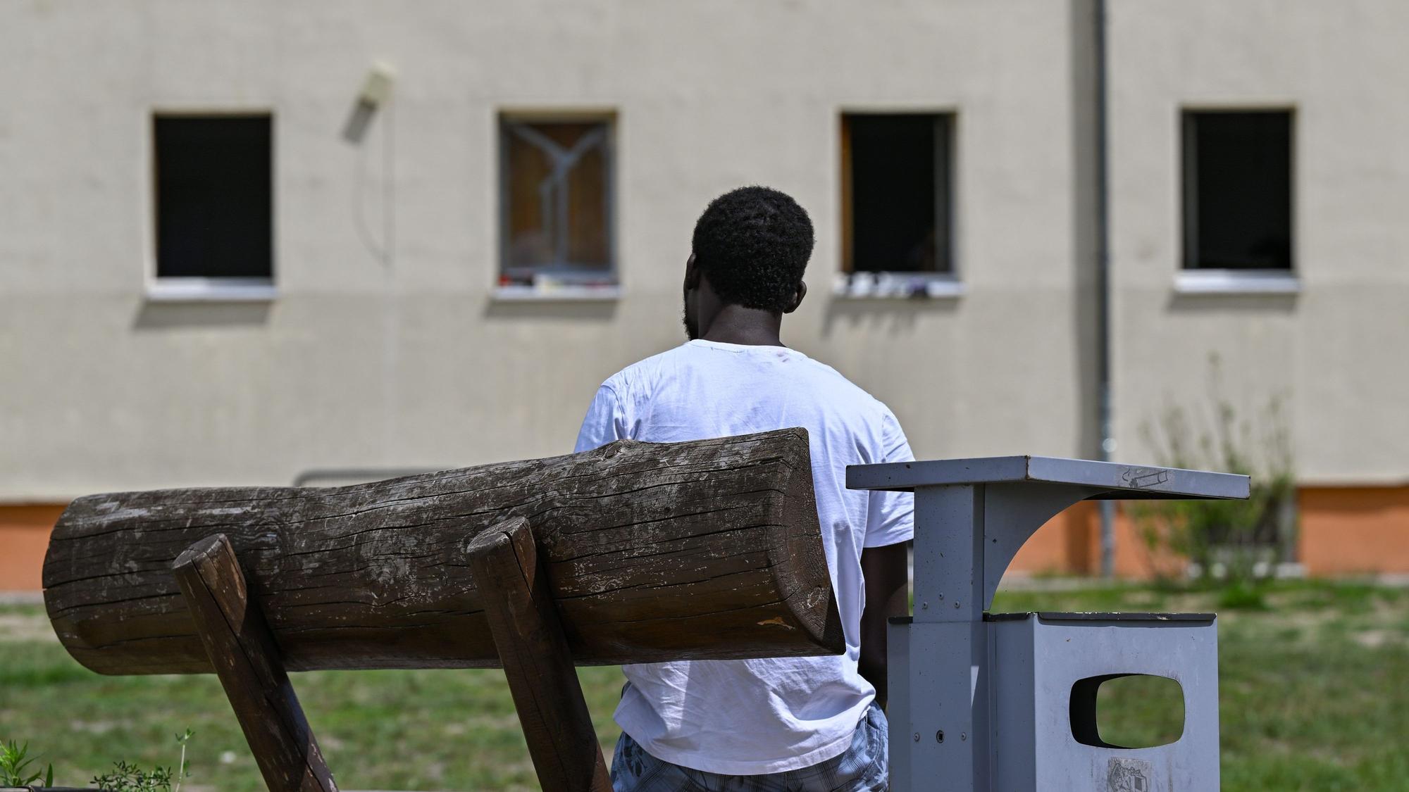 Ein Migrant sitzt auf einer Bank auf dem Gelände der Zentralen Erstaufnahmeeinrichtung für Asylbewerber (ZABH) des Landes Brandenburg.