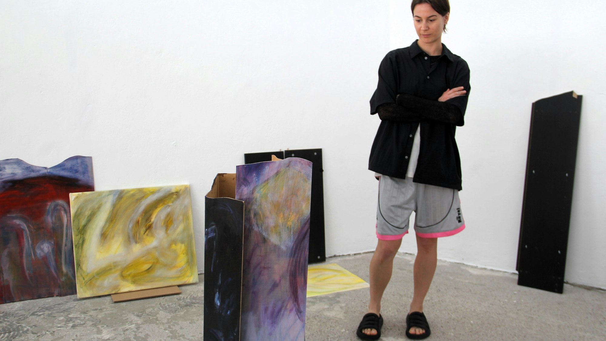 Kunstschaffende Person neben Kunstwerken