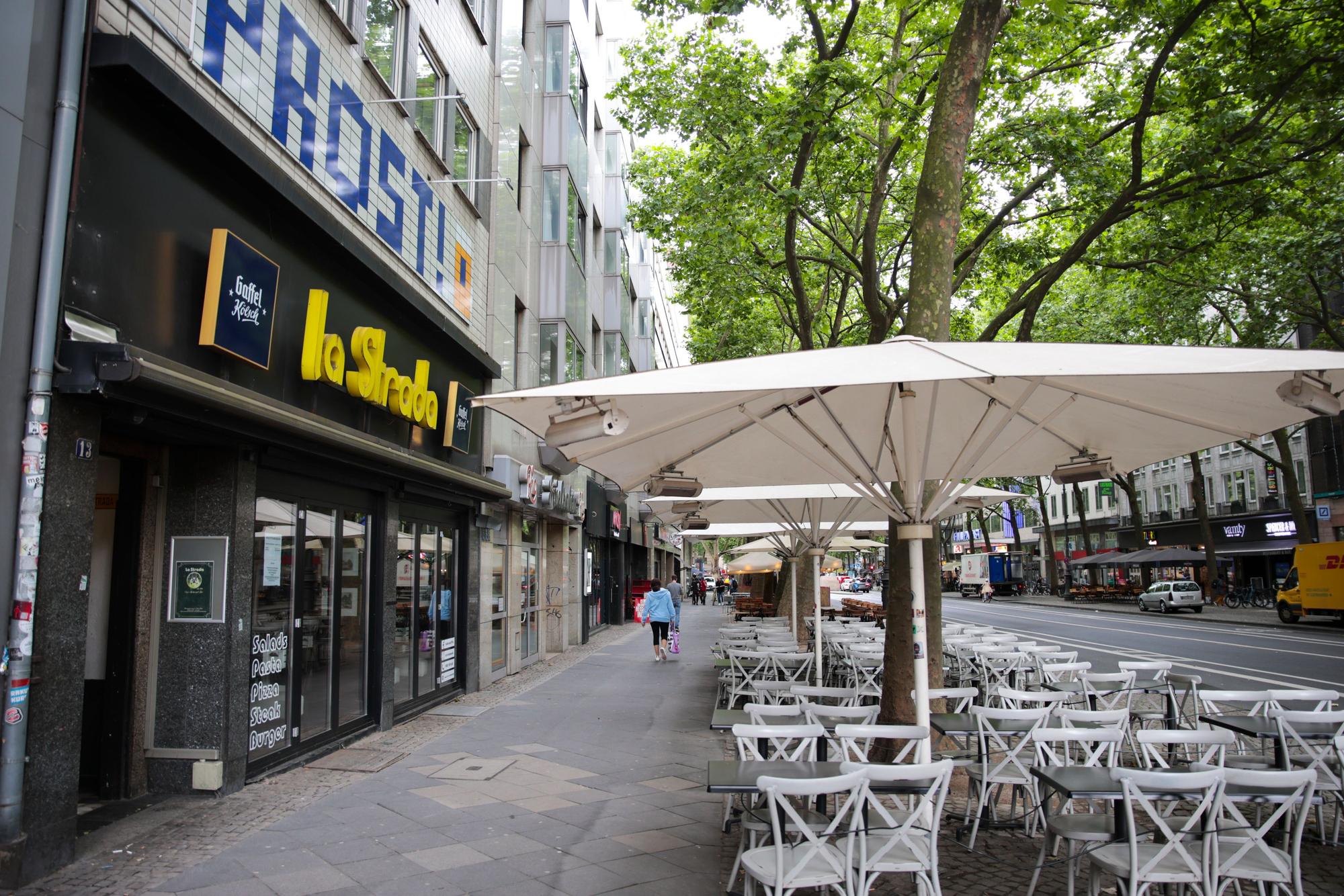 Fassade eines Restaurants und Stühle und Tische auf dem Gehweg davor.