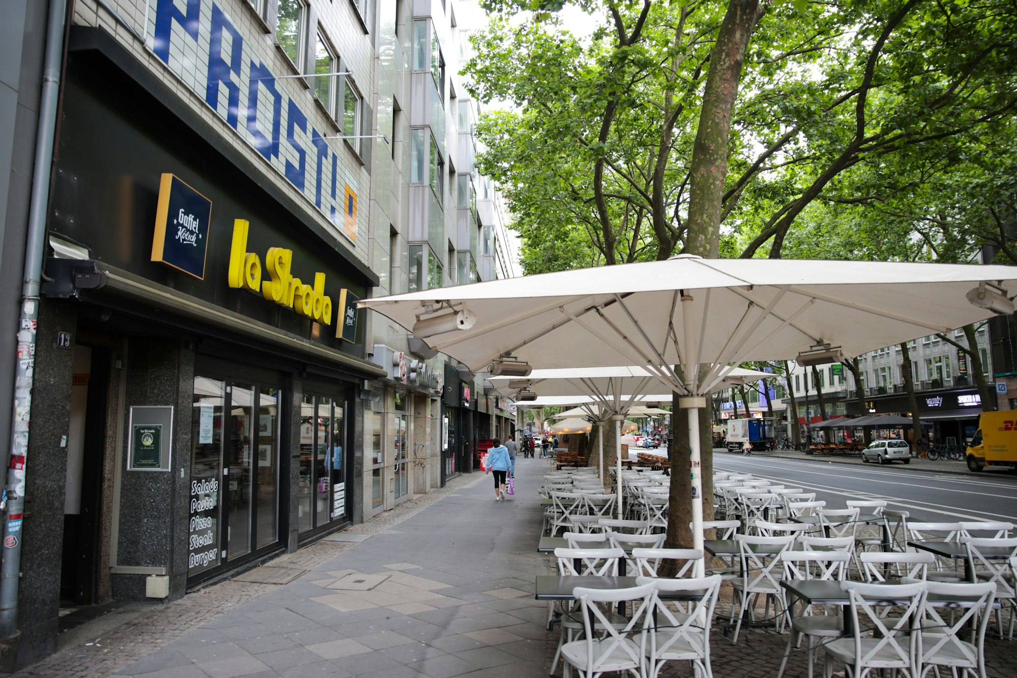 Fassade eines Restaurants und Stühle und Tische auf dem Gehweg davor.